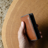 Hand holding a brown leather wallet on a wooden surface