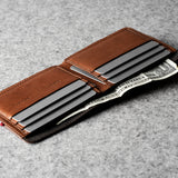 Brown leather wallet with money clip on a gray surface