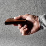 Hand holding a brown leather wallet against a gray background