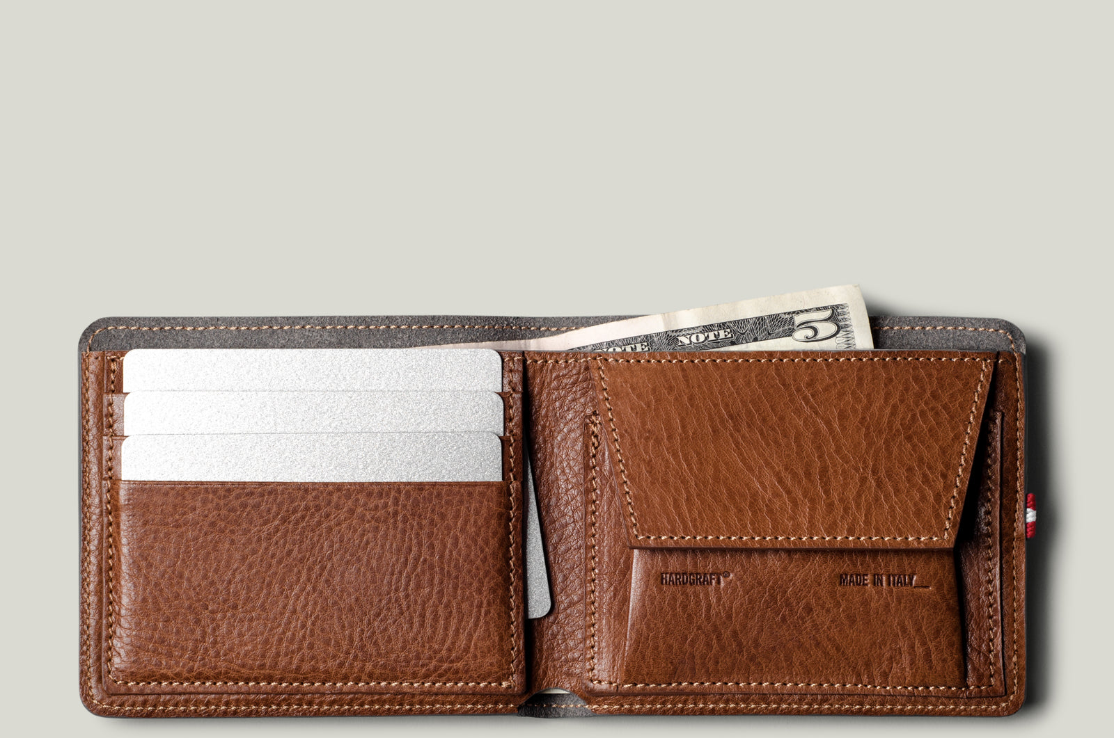 Brown leather wallet with money and cards on a light gray background