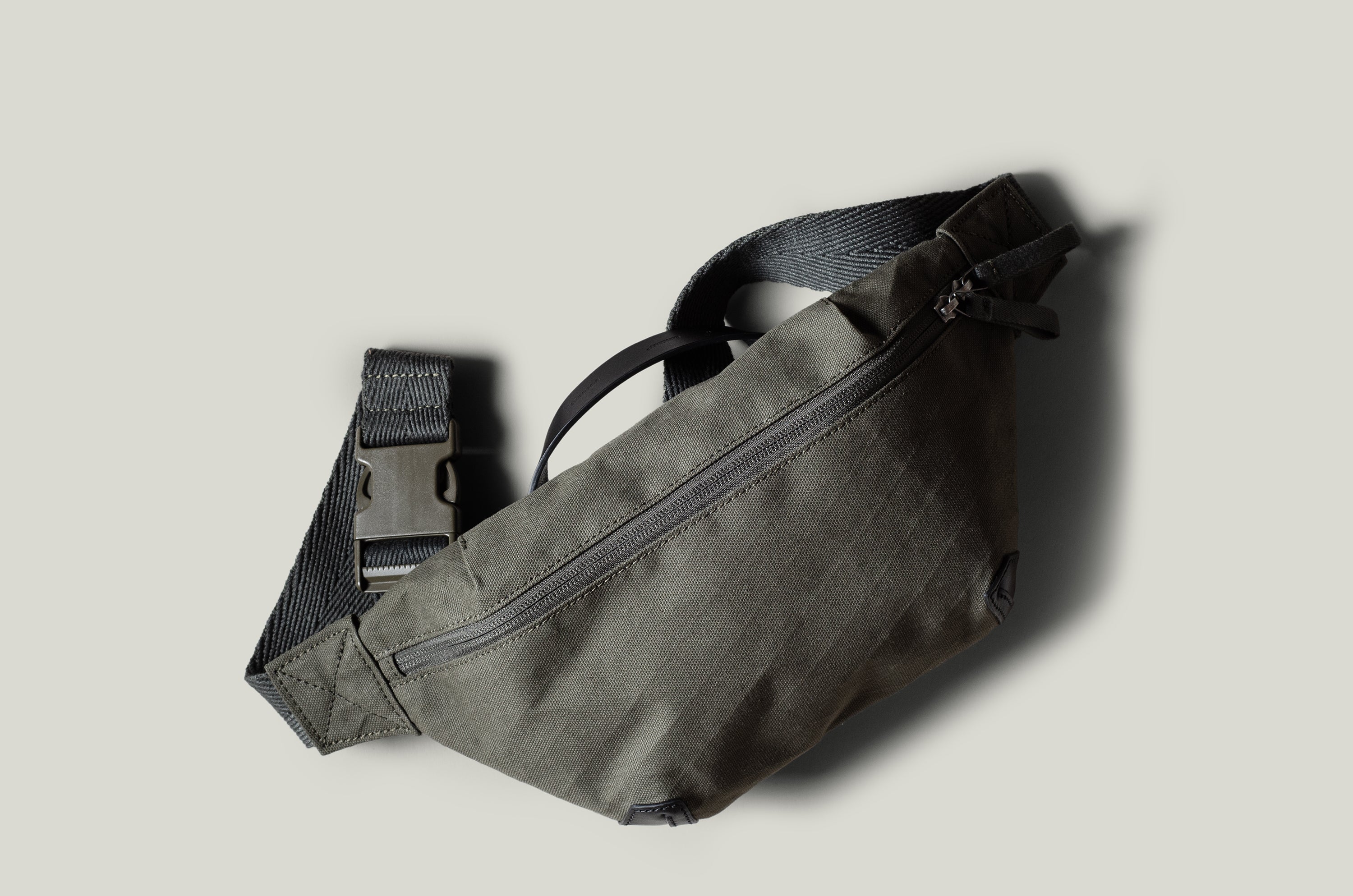 Green waist cross body bag with technical fabric and black leather details.