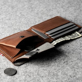 Brown leather wallet with money pocket and card slots on a gray surface