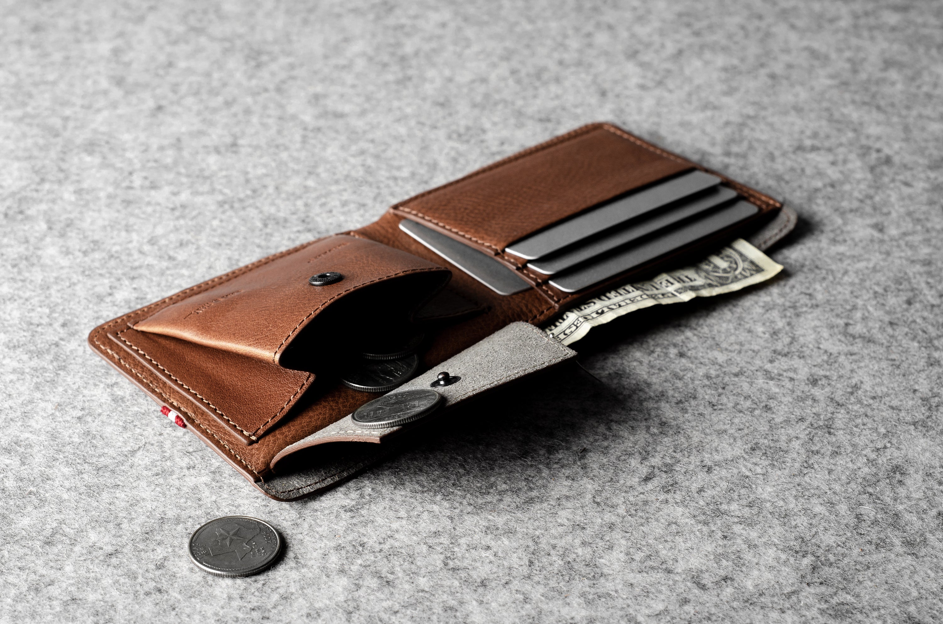 Brown leather wallet with money pocket and card slots on a gray surface