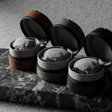 Three open leather watch cases on a marble surface