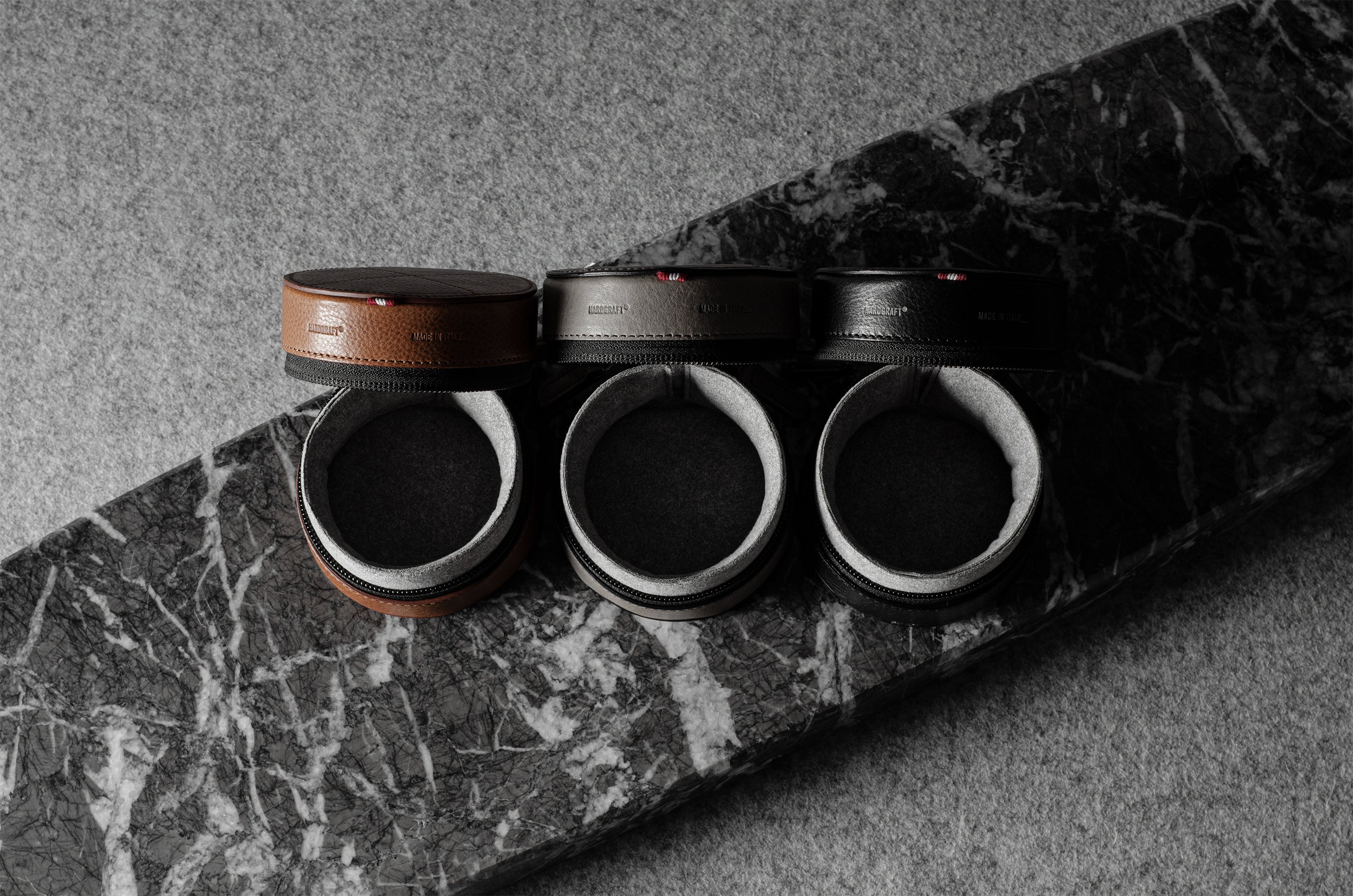 Three open leather watch cases on a marble surface