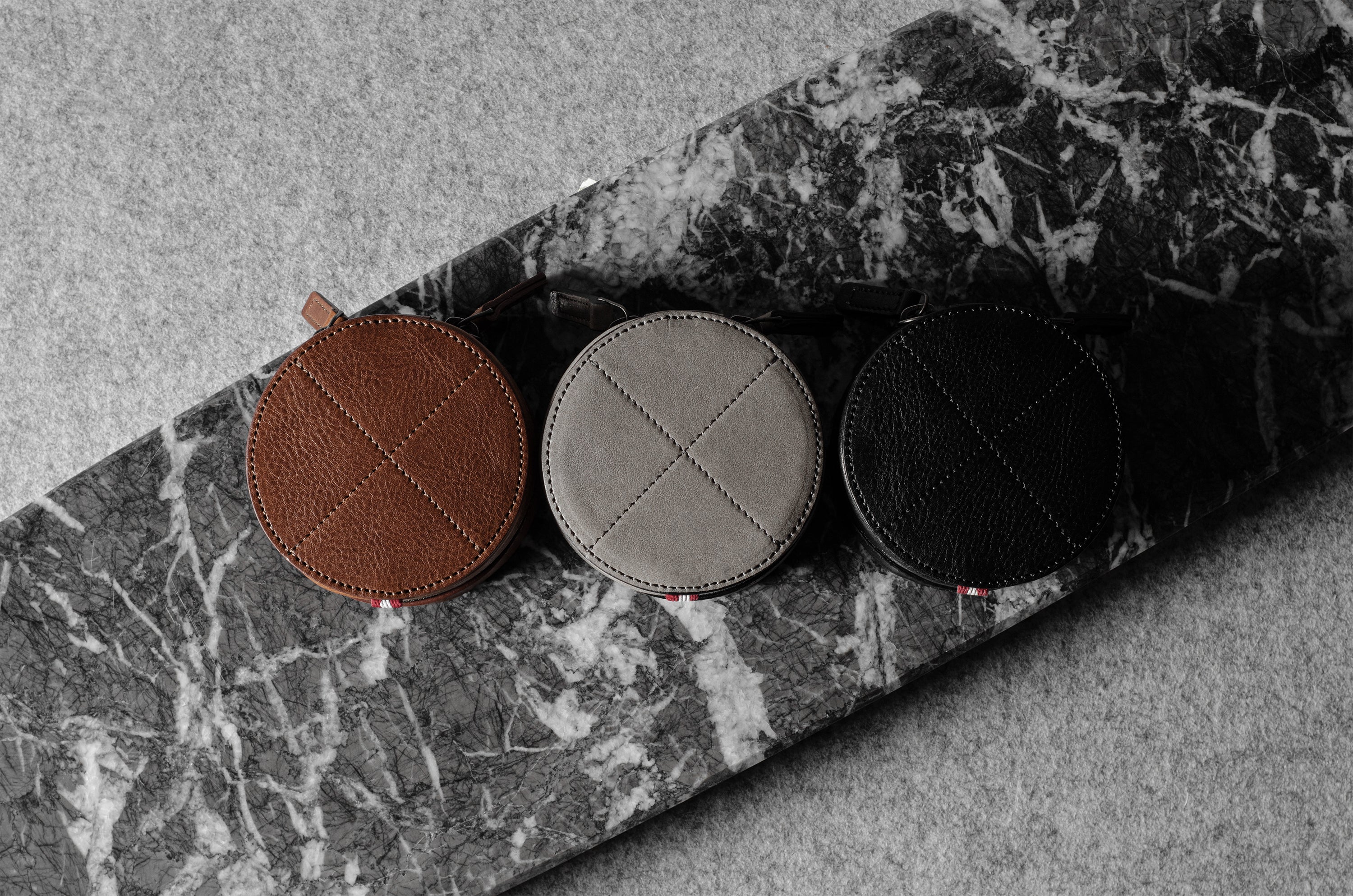 Three open leather watch cases on a marble surface