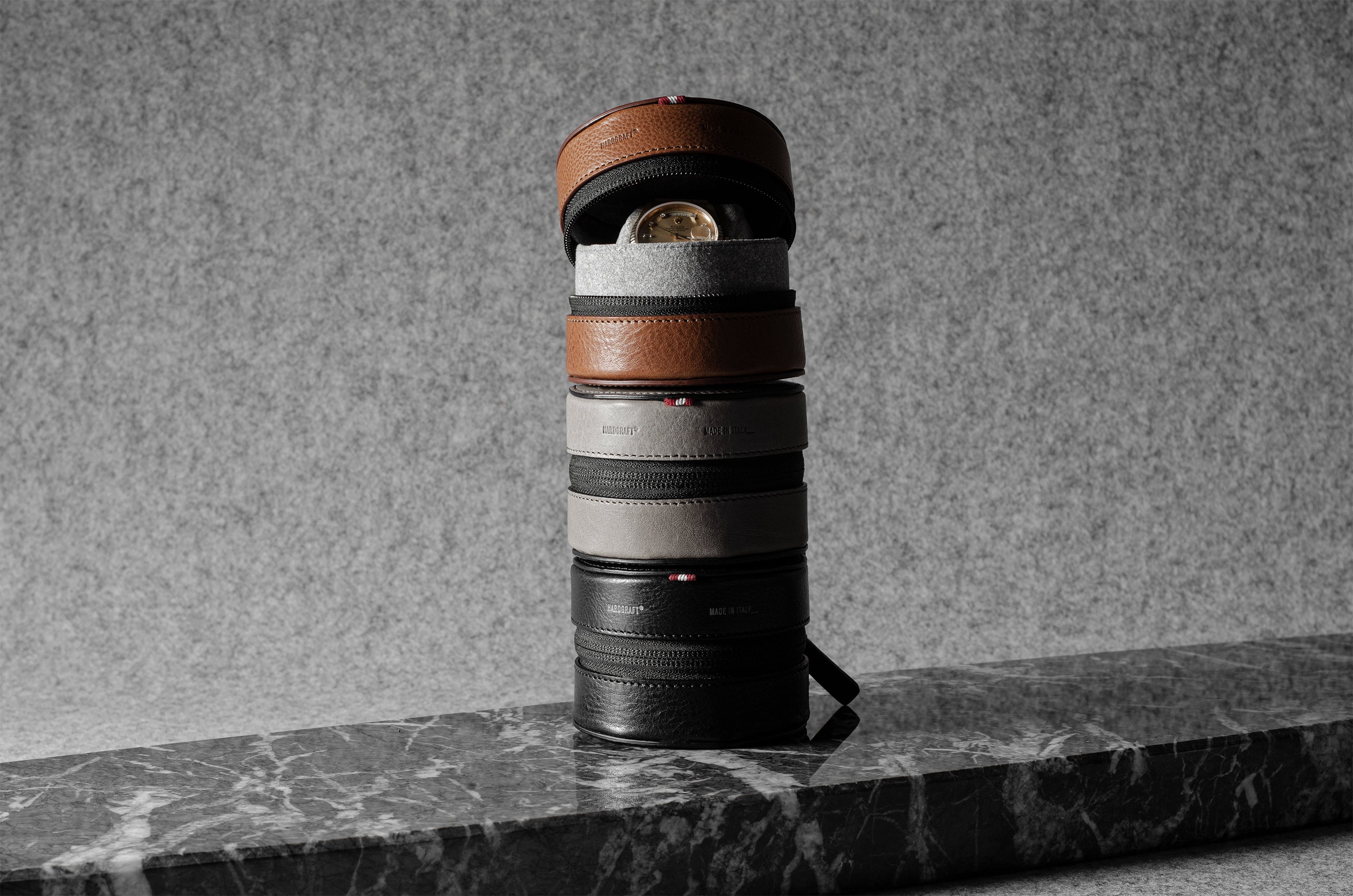 Stack of watch cases on a marble surface with a gray background