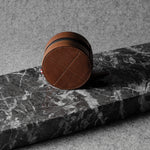 Brown leather watch case on a black marble surface with a gray background