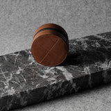 Brown leather watch case on a black marble surface with a gray background