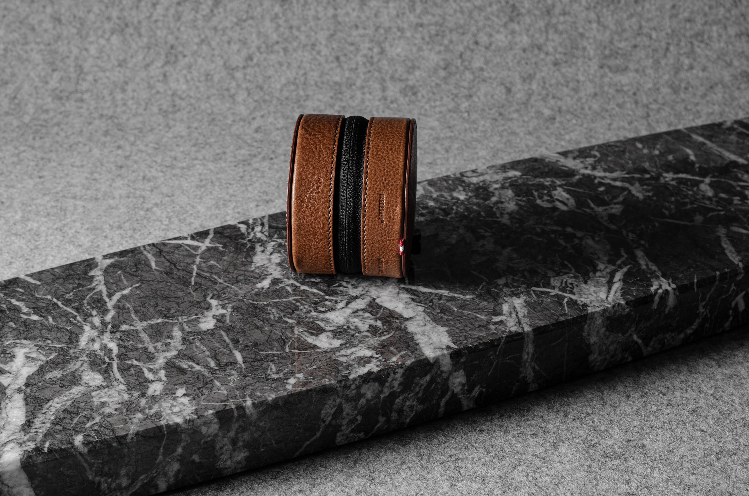 Brown leather watch case on a marble surface with a neutral background
