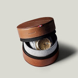 Brown leather watch case with a watch inside on a light gray background