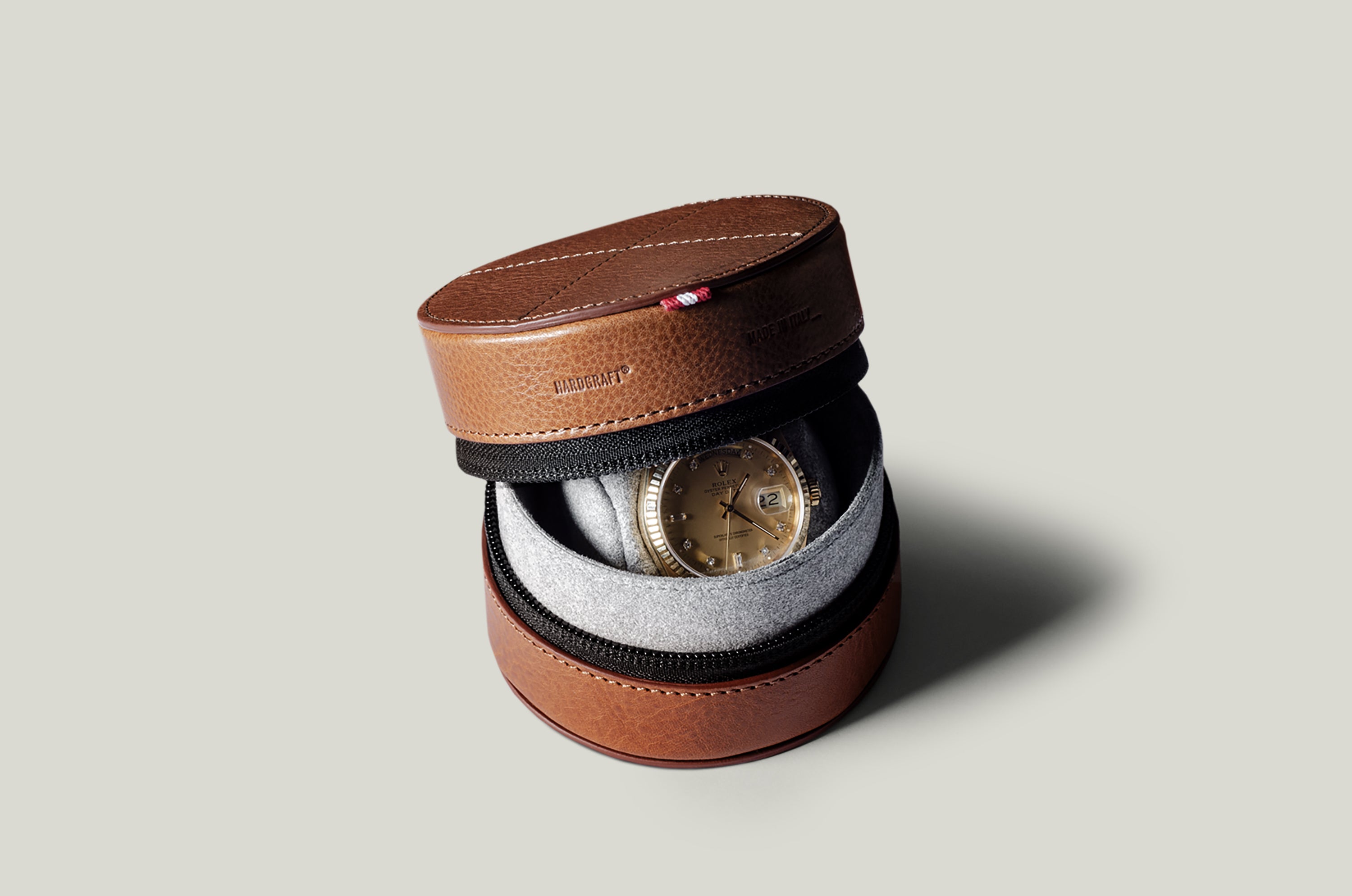 Brown leather watch case with a watch inside on a light gray background