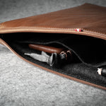 Brown leather laptop case with zipper on a gray surface
