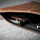 Brown leather laptop case with zipper on a gray surface