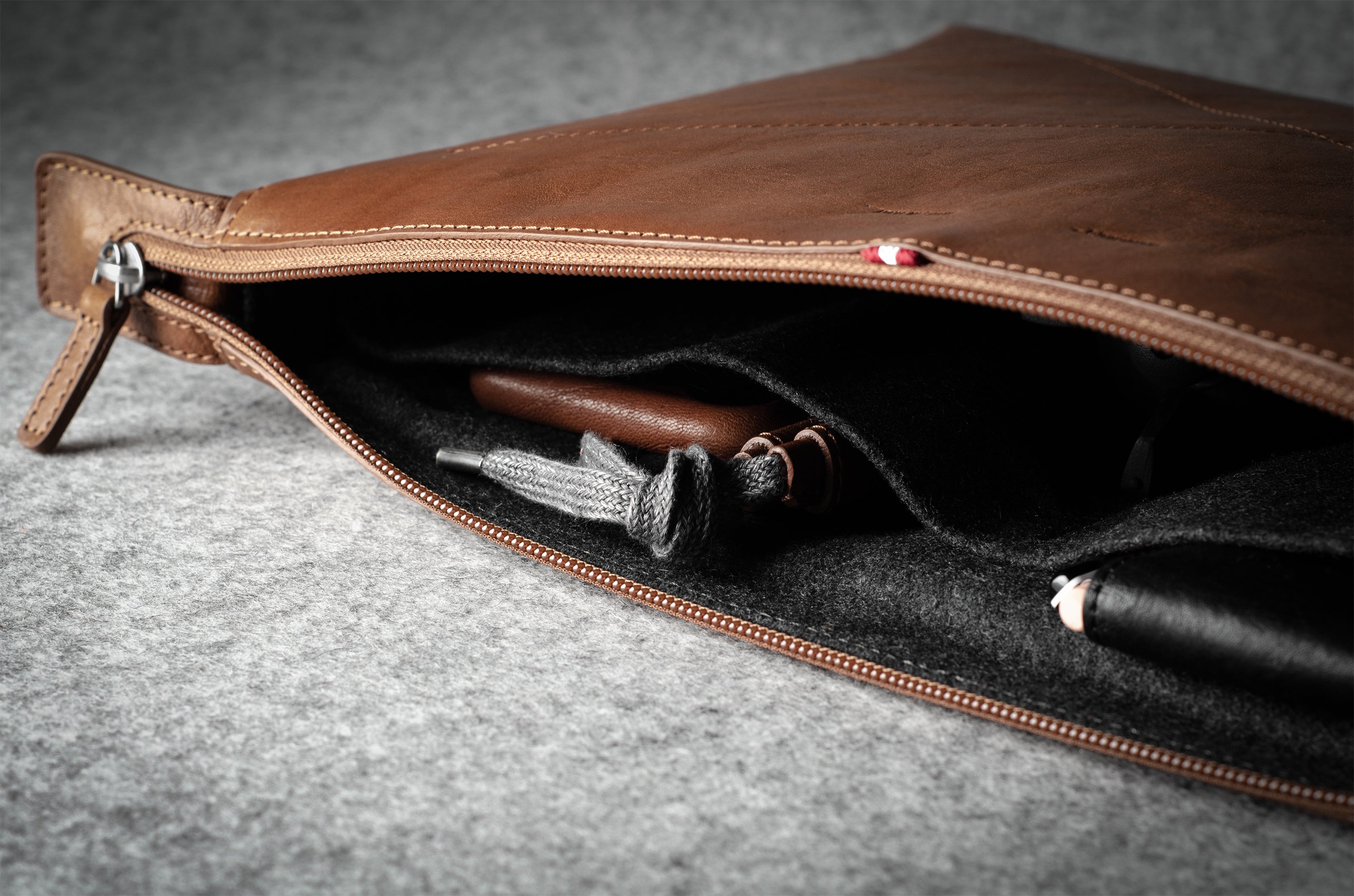 Brown leather laptop case with zipper on a gray surface