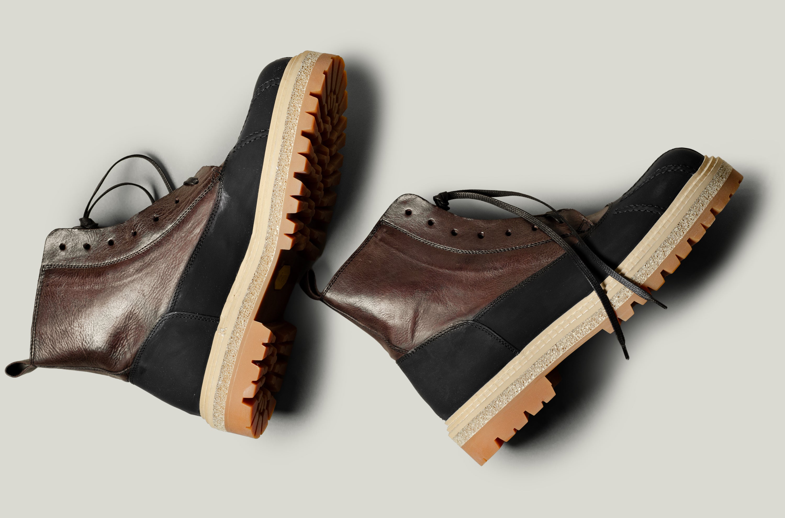 Pair of brown and black leather boots on a light gray background
