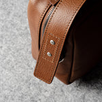 A classic brown leather shoulder bag with a zipper closure and an adjustable strap