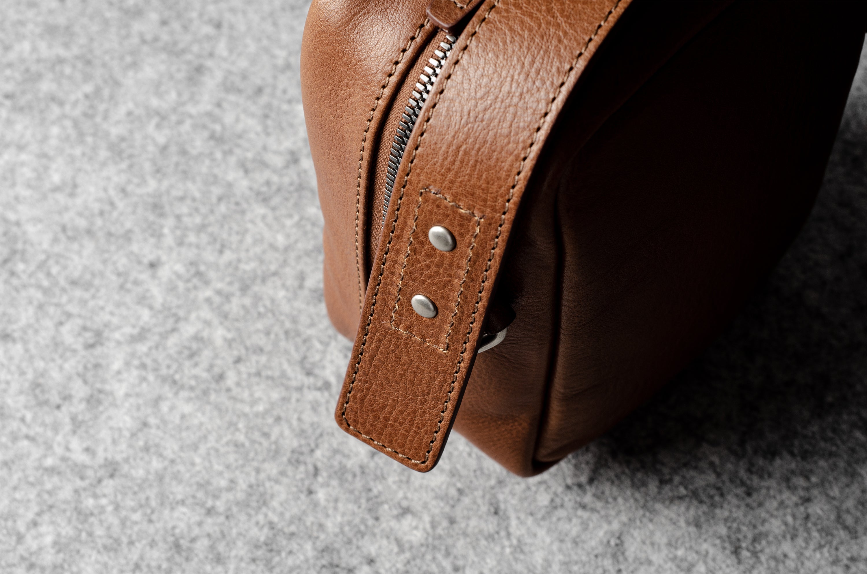 A classic brown leather shoulder bag with a zipper closure and an adjustable strap