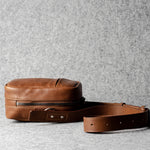 A classic brown leather shoulder bag with a zipper closure and an adjustable strap