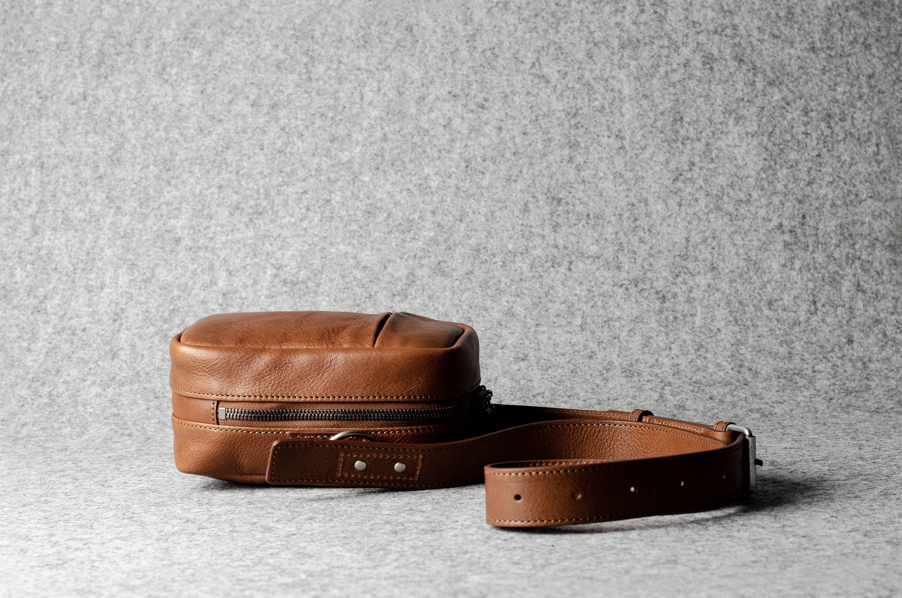 A classic brown leather shoulder bag with a zipper closure and an adjustable strap