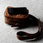 A classic brown leather shoulder bag with a zipper closure and an adjustable strap