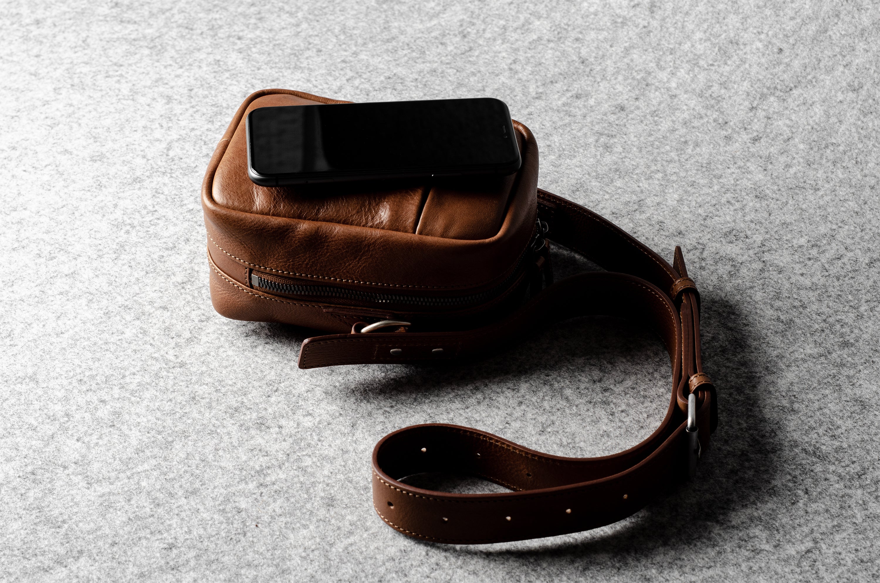 A classic brown leather shoulder bag with a zipper closure and an adjustable strap