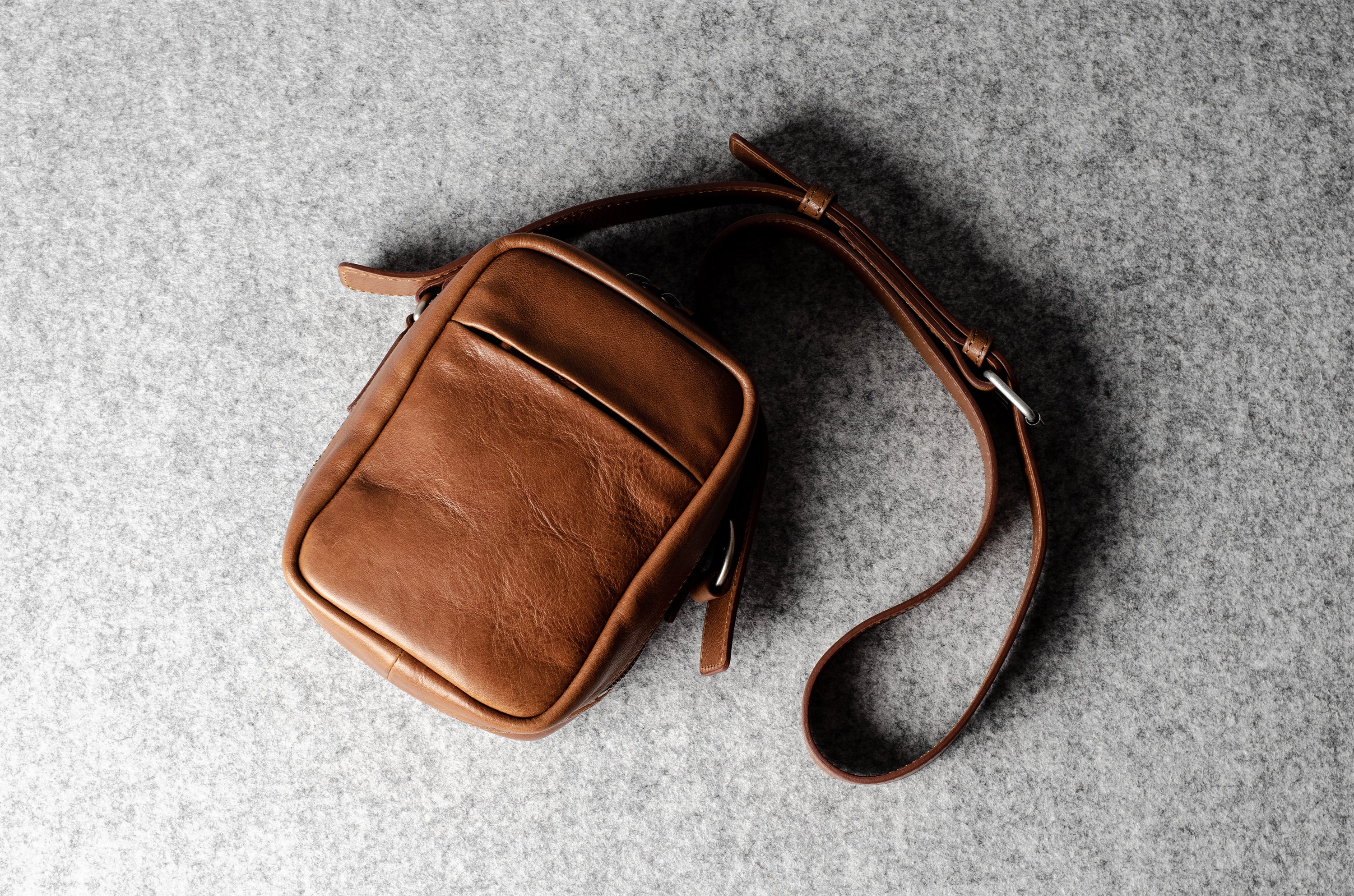 A classic brown leather shoulder bag with a zipper closure and an adjustable strap