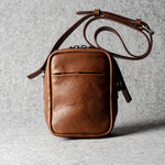 A classic brown leather shoulder bag with a zipper closure and an adjustable strap