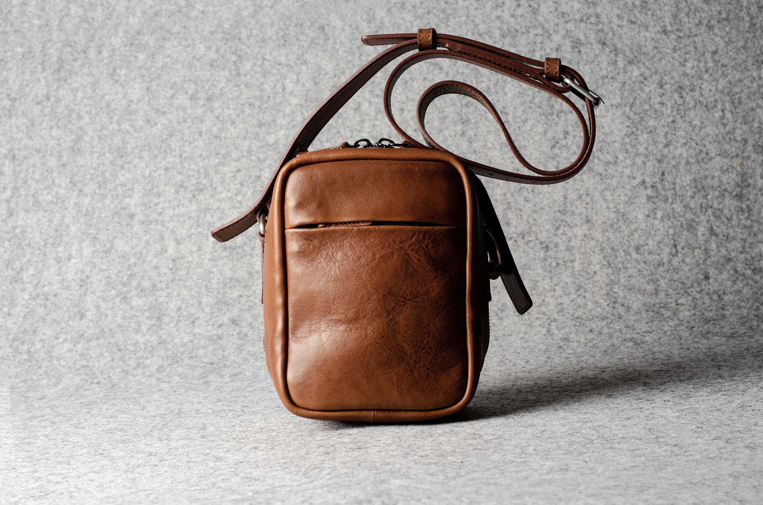 A classic brown leather shoulder bag with a zipper closure and an adjustable strap
