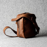A classic brown leather shoulder bag with a zipper closure and an adjustable strap