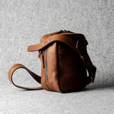 A classic brown leather shoulder bag with a zipper closure and an adjustable strap