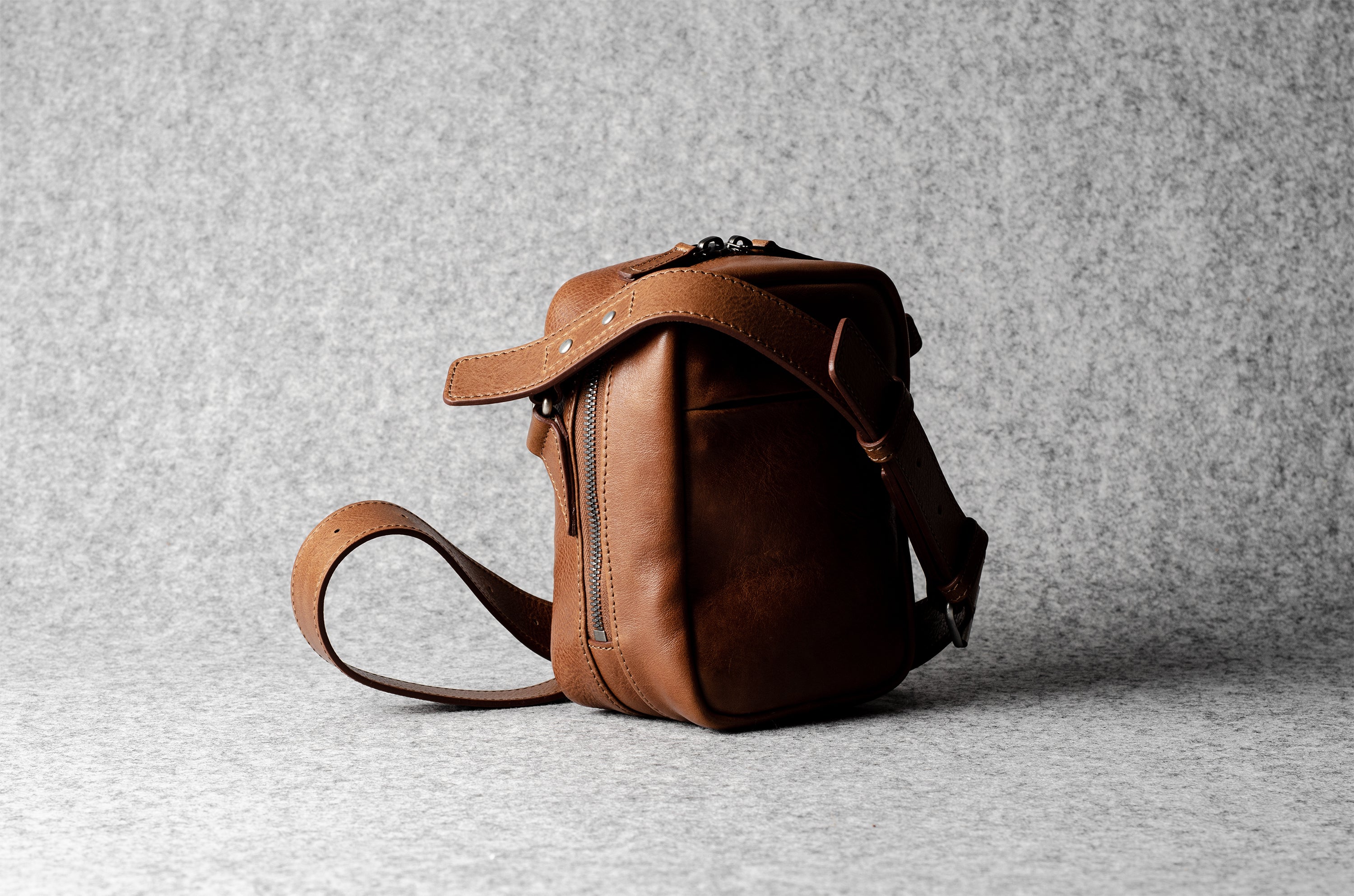 A classic brown leather shoulder bag with a zipper closure and an adjustable strap