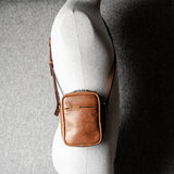 A classic brown leather shoulder bag with a zipper closure and an adjustable strap