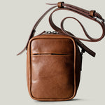 A classic brown leather shoulder bag with a zipper closure and an adjustable strap, made in Italy.