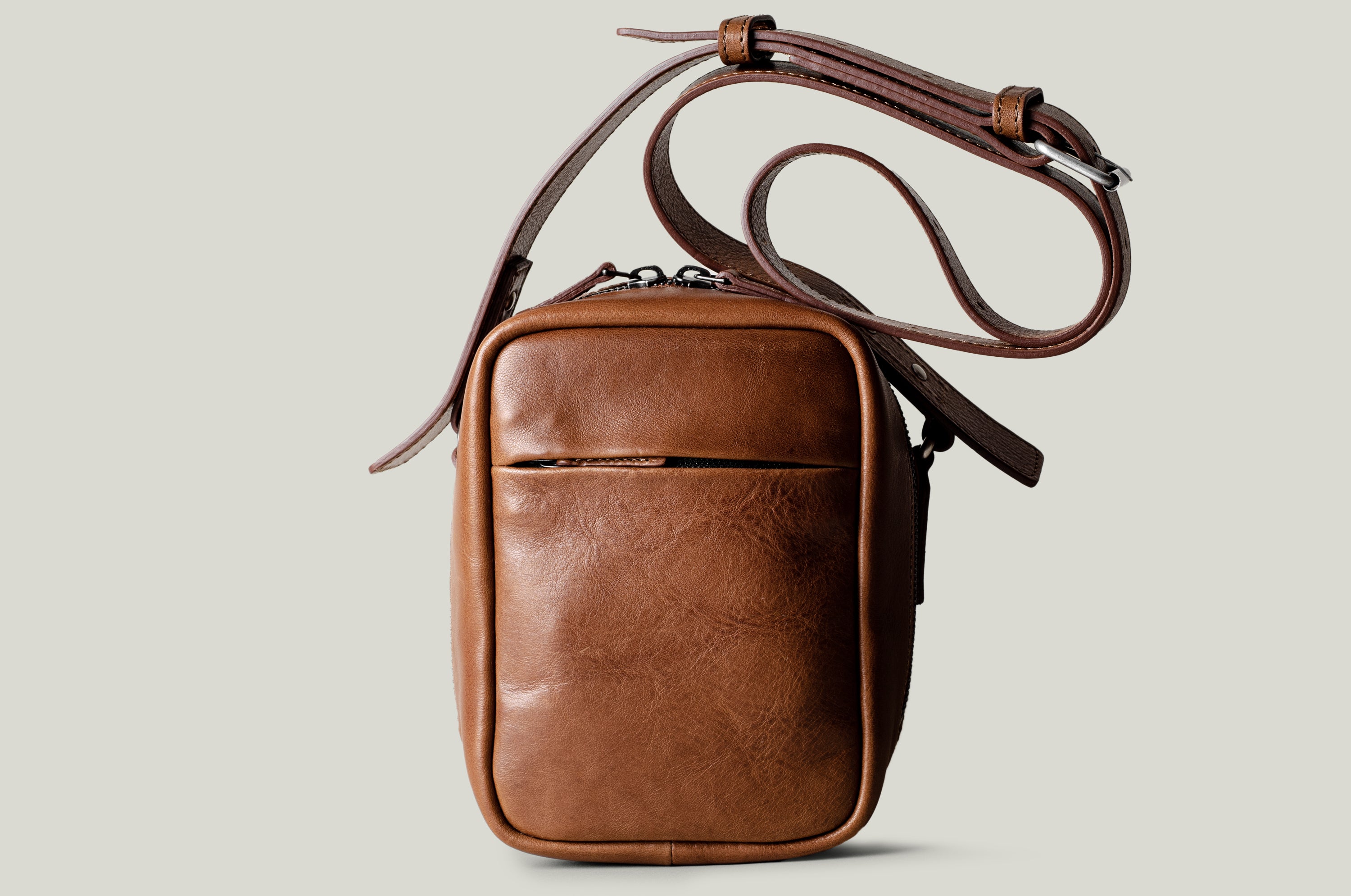 A classic brown leather shoulder bag with a zipper closure and an adjustable strap, made in Italy.