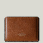 Brown leather passport wallet on a light gray background
