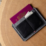 Black and gray wallet with passport and money on a wooden surface