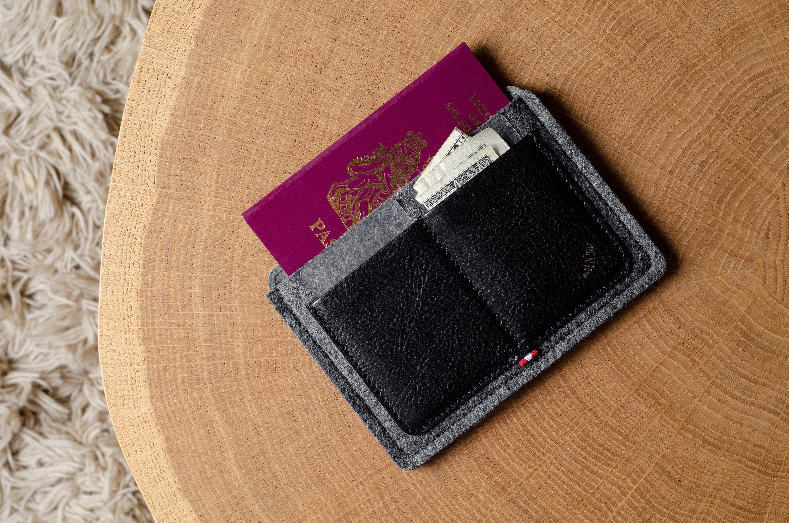 Black and gray wallet with passport and money on a wooden surface