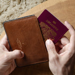 Brown leather passport wallet with a passport held open on a wooden surface.