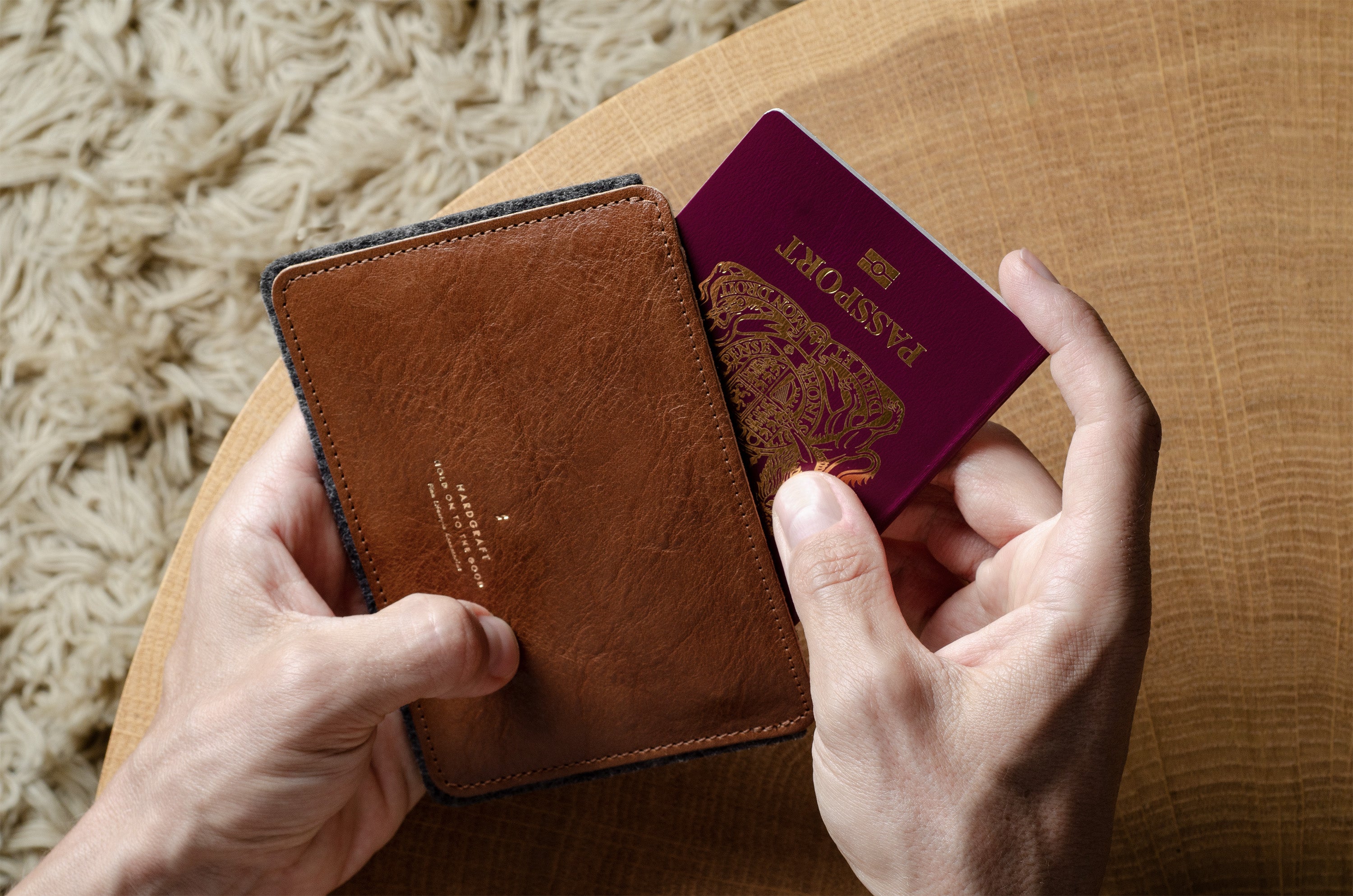 Brown leather passport wallet with a passport held open on a wooden surface.
