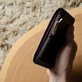 Hand holding a black passport wallet on a textured surface