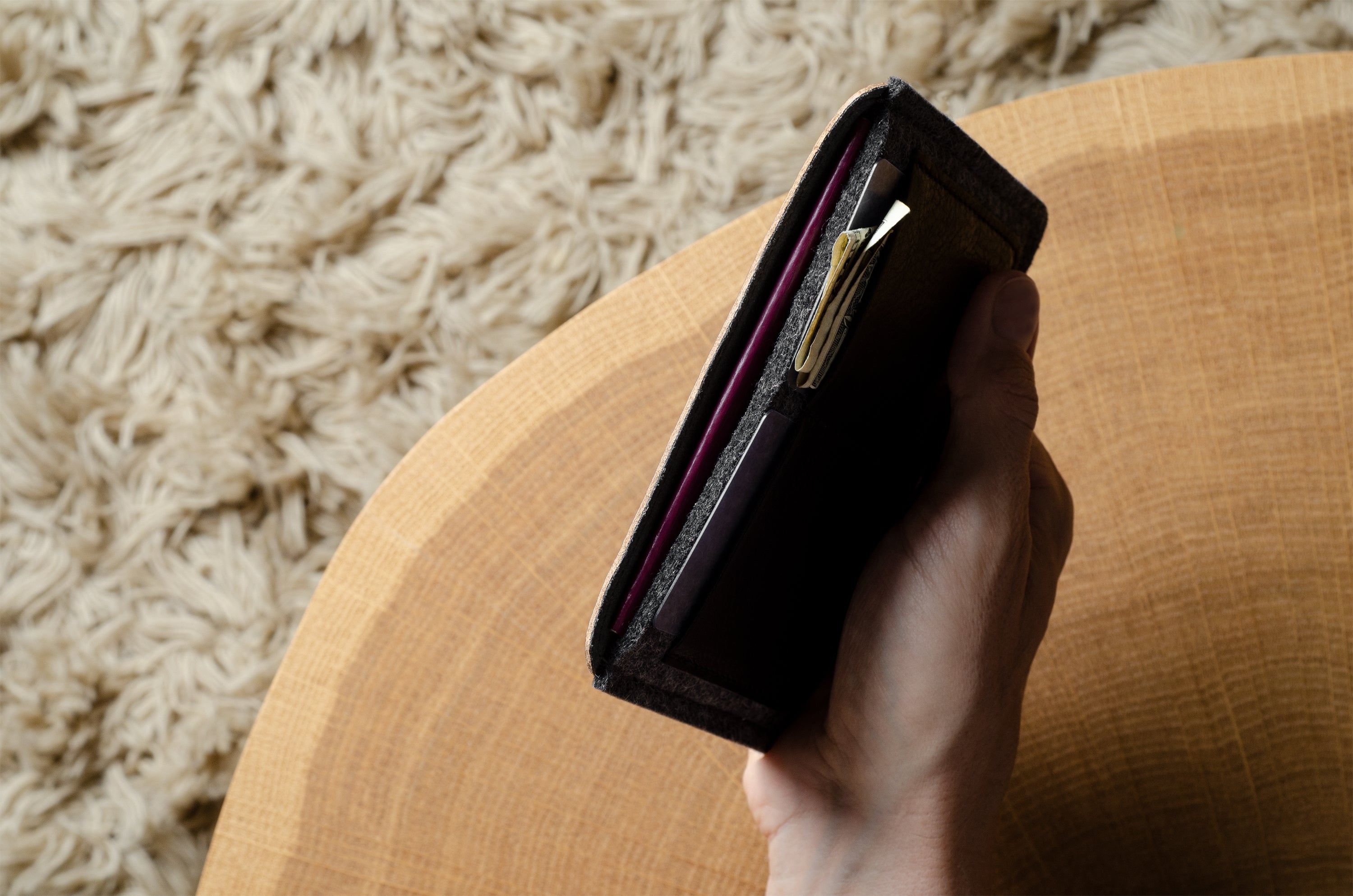 Hand holding a black passport wallet on a textured surface