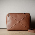 Brown leather bag with X detail and shoulder strap.
