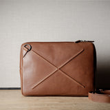 Brown leather bag with X detail and shoulder strap.