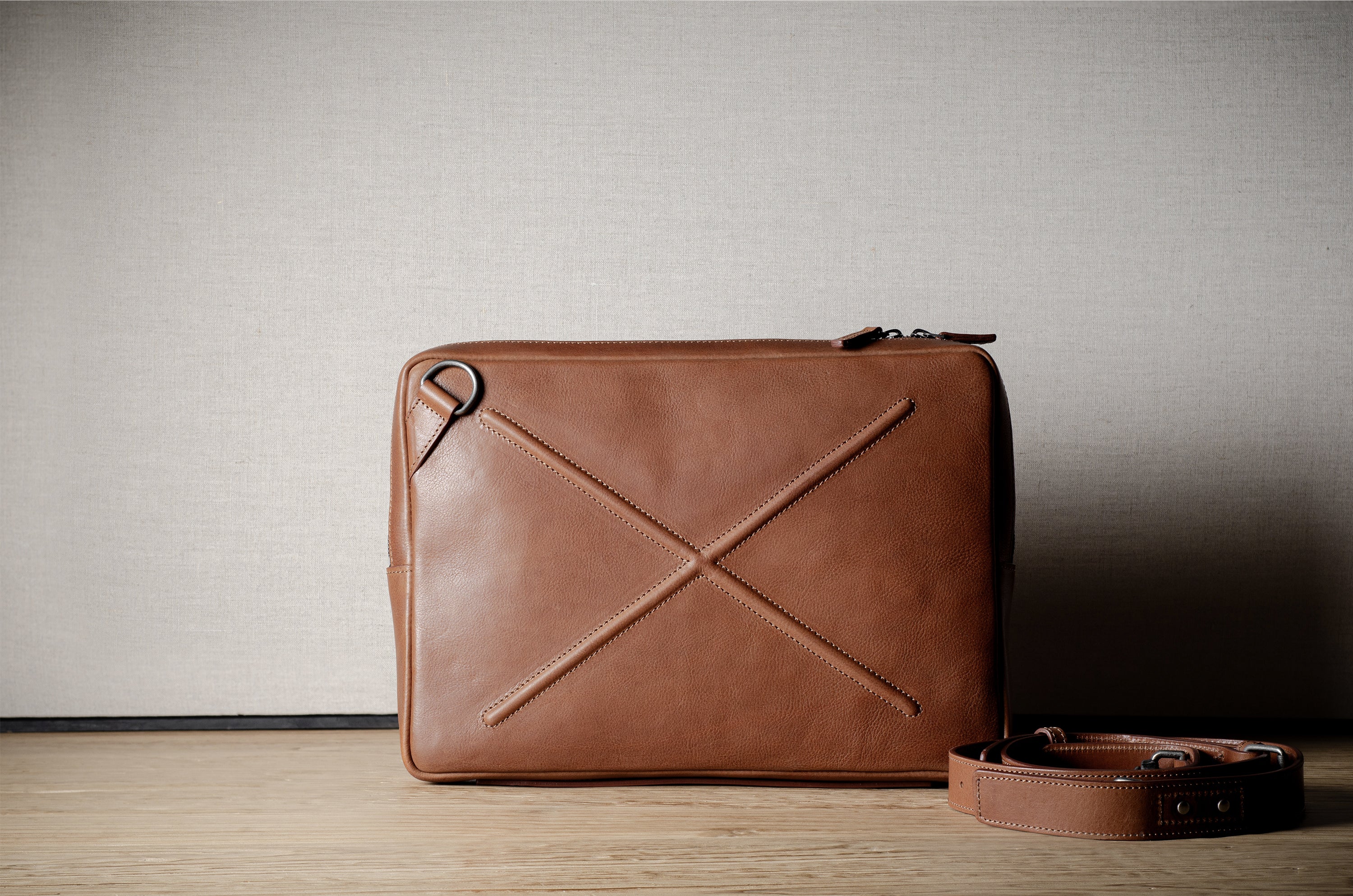 Brown leather bag with X detail and shoulder strap.