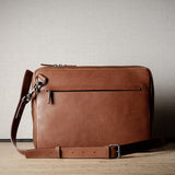 Brown leather bag with X detail and shoulder strap.