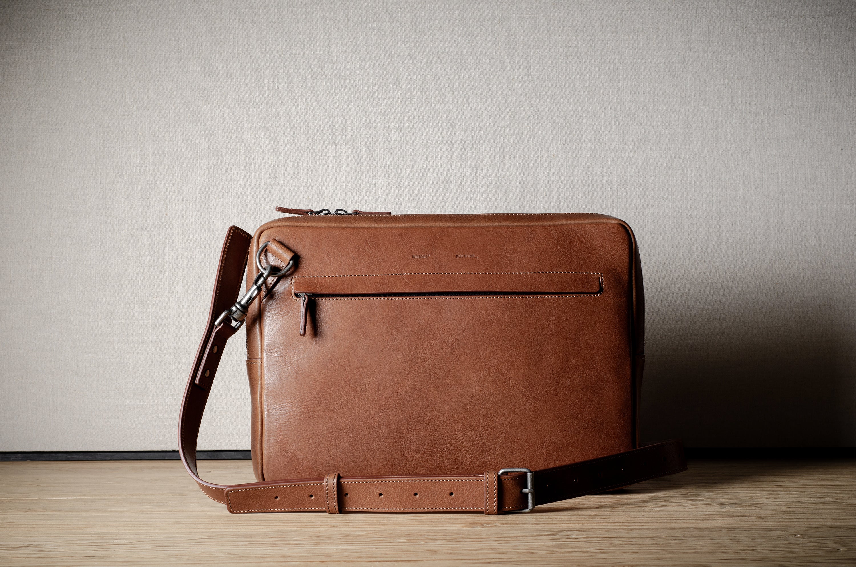 Brown leather bag with X detail and shoulder strap.