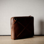 Brown leather bag with X detail and shoulder strap.