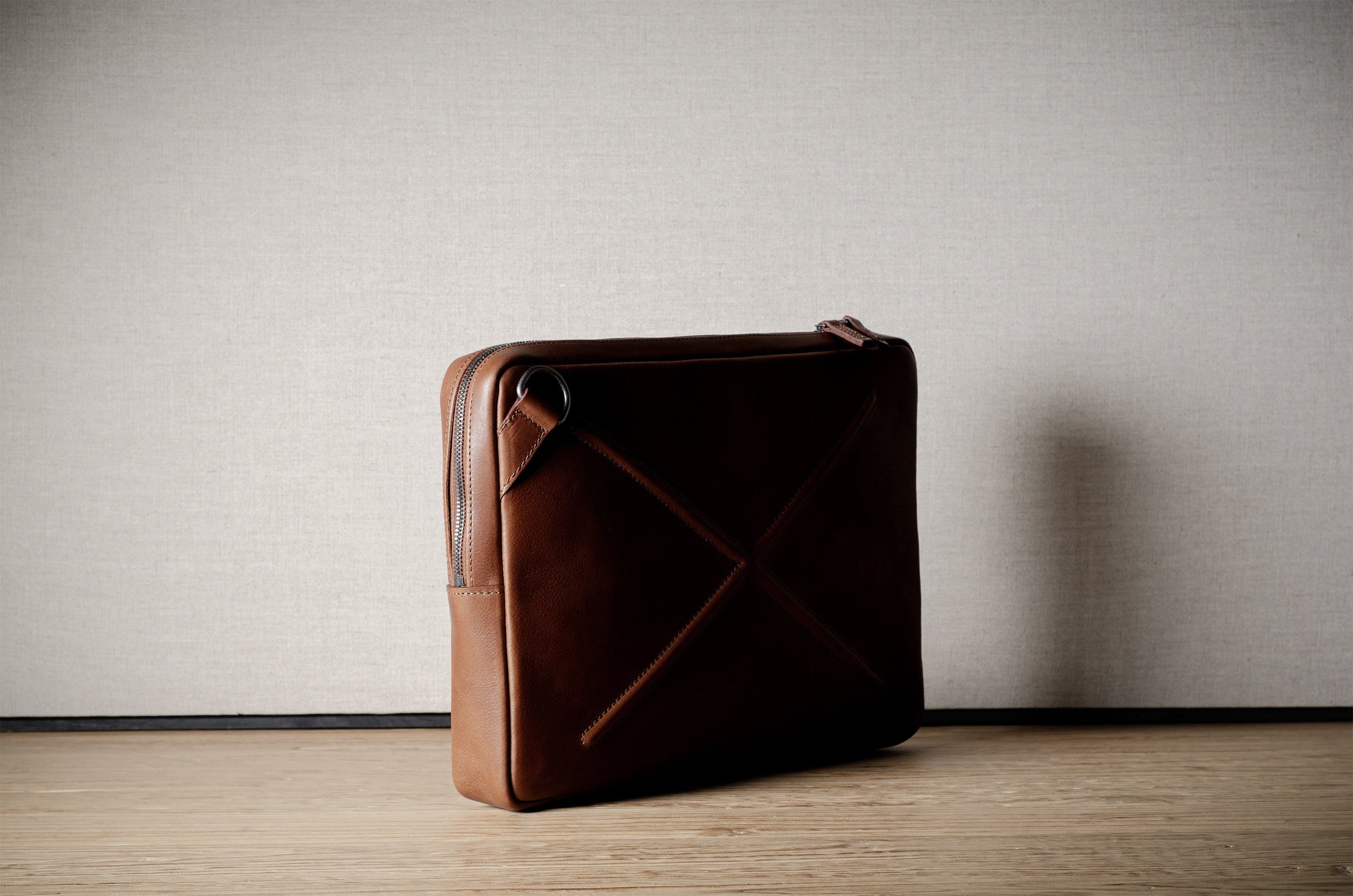 Brown leather bag with X detail and shoulder strap.