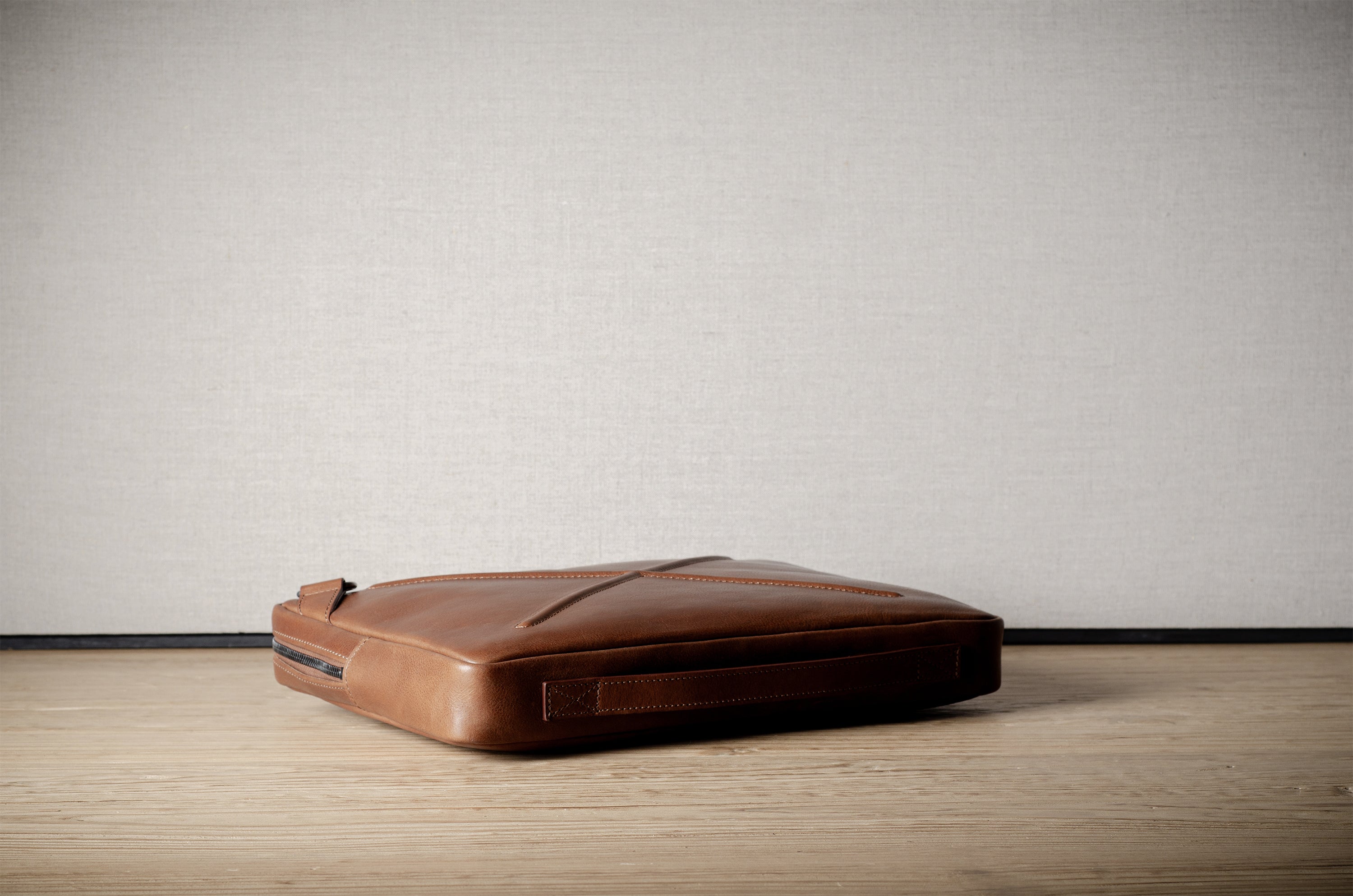 Brown leather bag with X detail and shoulder strap.